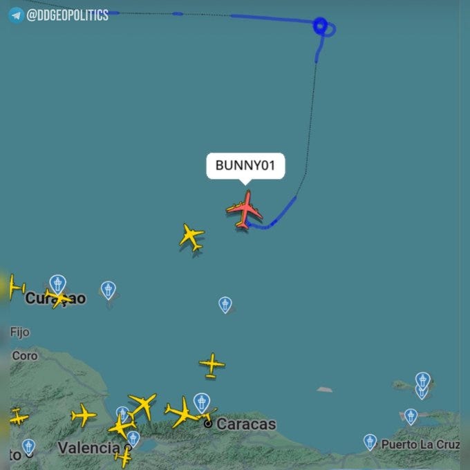 Flight tracking map displays blue curved paths of aircraft over a green and blue terrain map of Venezuela, with red airplane icons indicating BUNNY01 positions near Puerto La Cruz, Curacao, and Caracas. Yellow airplane icons mark locations in Valencia and other areas. Labels include BUNNY01, altitudes at 26000 feet, ground speeds, and place names like Caracas and Valencia. Watermarks from DD_Geopolitics and Flightradar24 are visible in corners.
