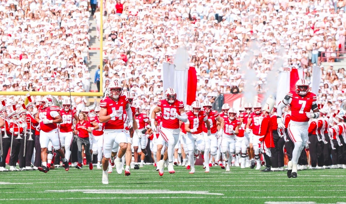 Wisconsin Badgers football players run onto the field at Camp Randall Stadium before a game.