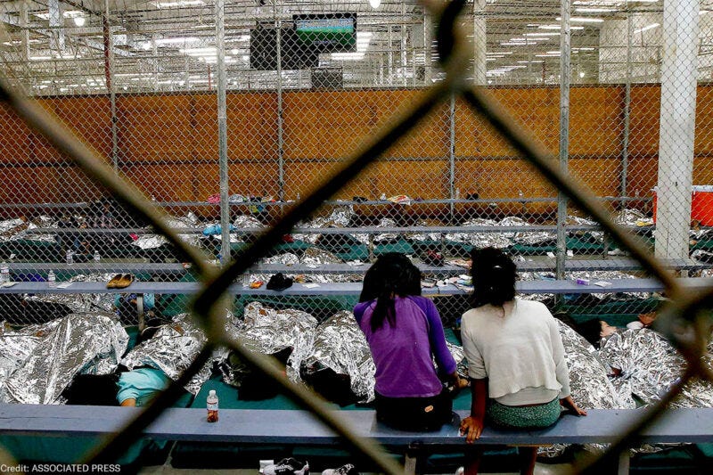 Two young girls watch a World Cup soccer match on a television from their holding area where hundreds of mostly Central American immigrant children are being processed and held Two young girls watch a World Cup soccer match on a television from their holding area where hundreds of mostly Central American immigrant children are being processed and held
