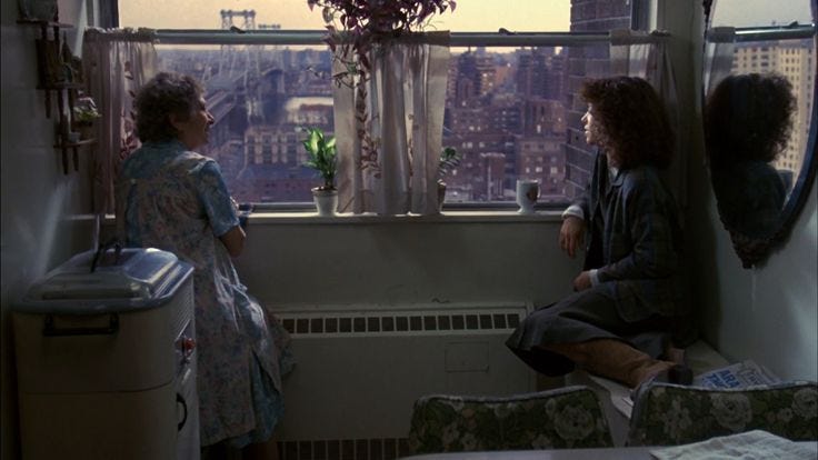 This may contain: two women sitting in front of a window looking out at the cityscape outside