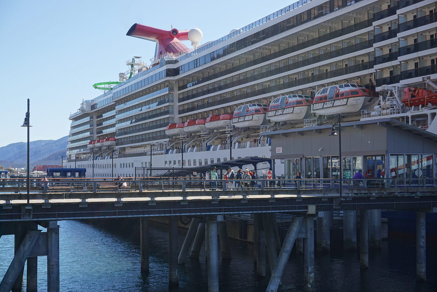 Passengers walk between a crusie ship and downtown Juneau's dock on April 26, 2024. (Photo by Yereth Rosen/Alaska Beacon) Passengers walk between a crusie ship and downtown Juneau's dock on April 26, 2024. (Photo by Yereth Rosen/Alaska Beacon)
