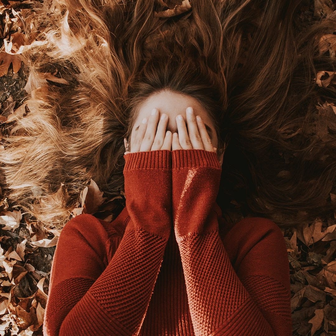 a woman laying on top of a pile of leaves