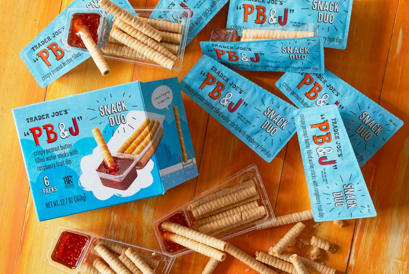 Trader Joe's PB&J Snack Duo packages scattered on surface, some opened and cookies dipped in fruit