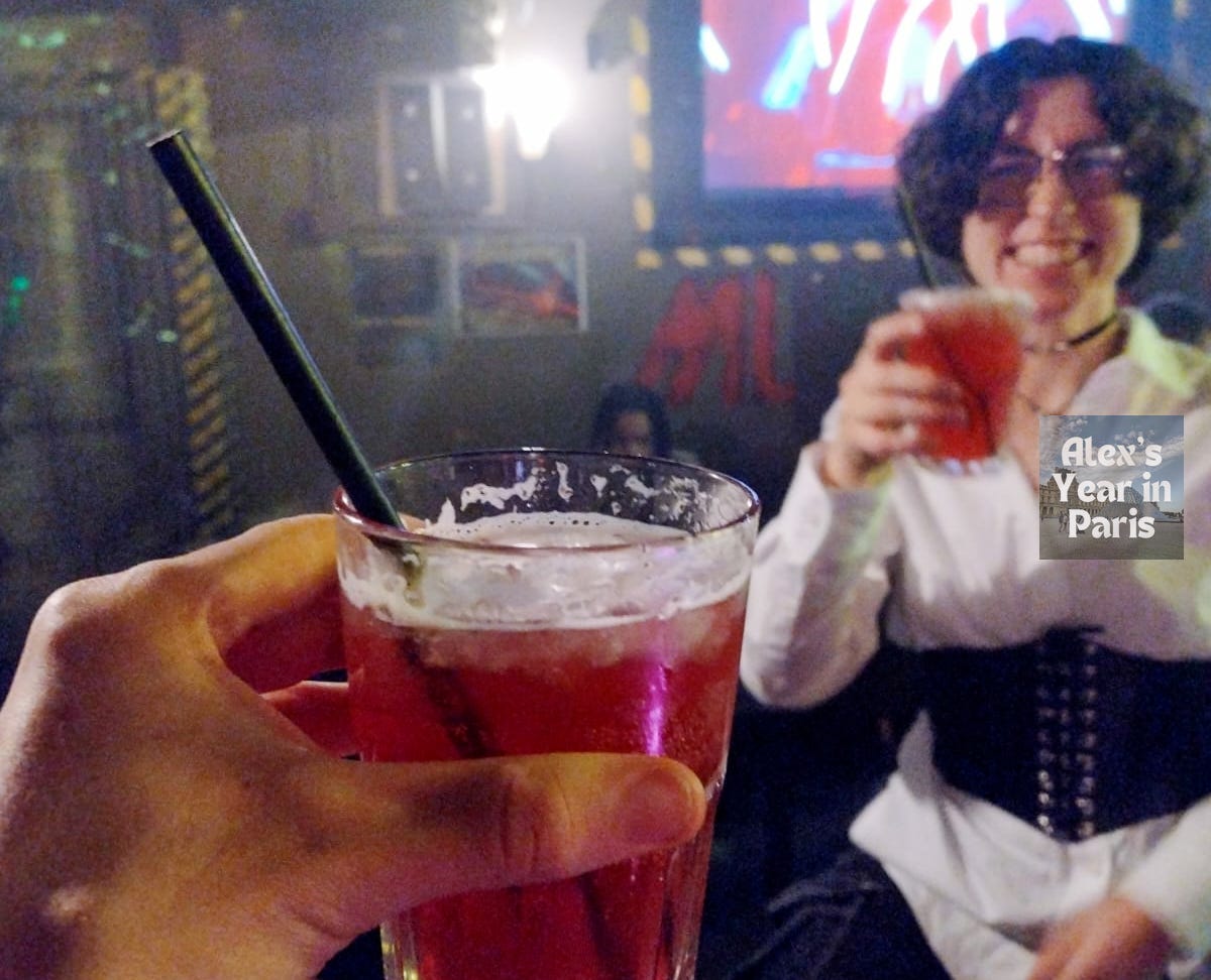 Holding a drink towards Lucie