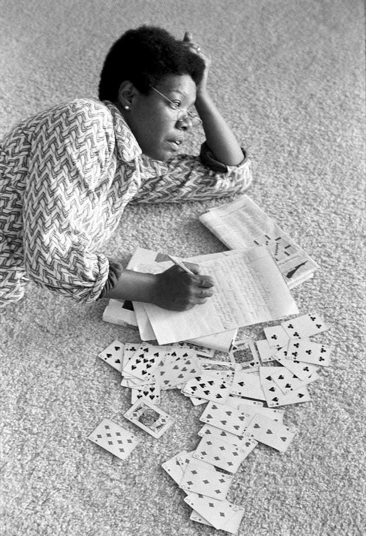 This may contain: a woman is sitting on the floor with playing cards in front of her and reading a book This may contain: a woman is sitting on the floor with playing cards in front of her and reading a book
