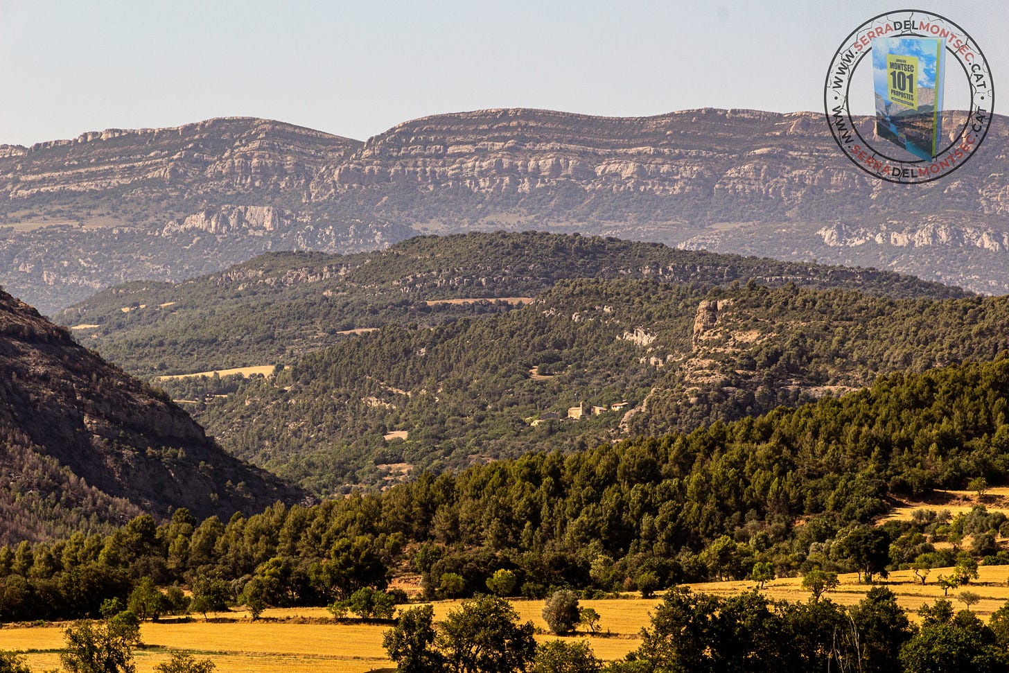 Gairebé al mig de la fotografia apareix la Clua en mig del paisatge i elevada sobre la vall d’Ariet (esquerra). Al fons, el Montsec de Rúbies (o de Meià). La Noguera, Lleida, Catalunya.