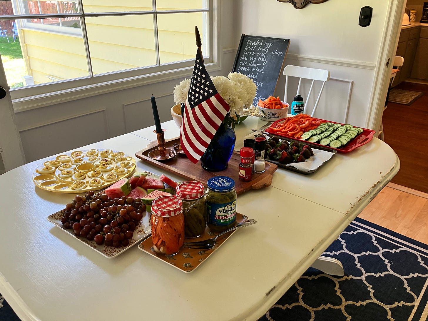Fourth of July table setting with US flag, fruits and vegetables, and a chalk board menu