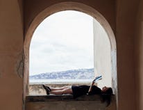 A girl reading by an open window.