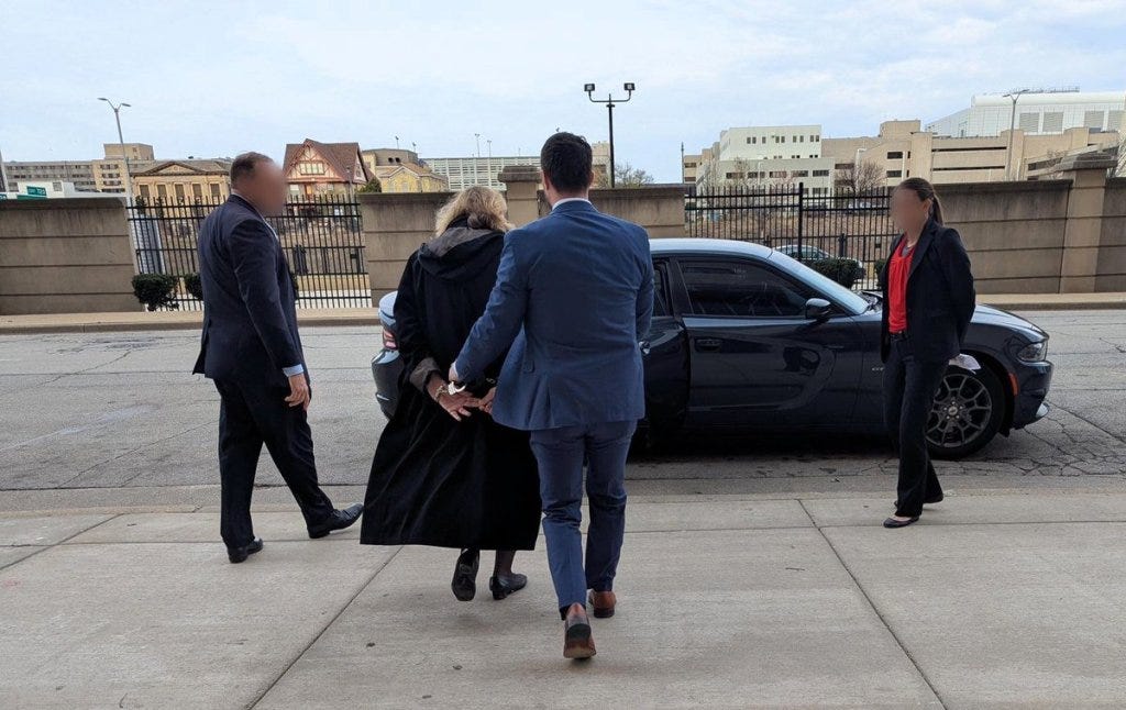 Judge Dugan is led to a car by officials after her arrest.