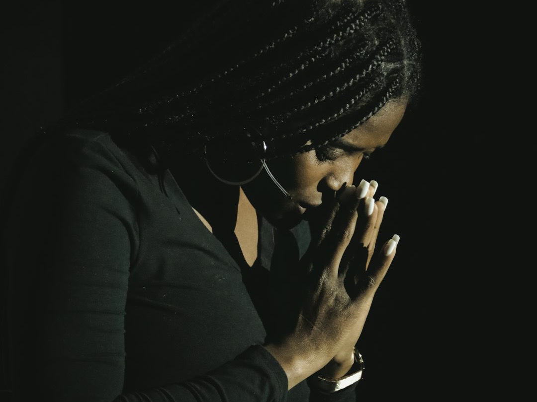 a woman in a black shirt is holding her hands together