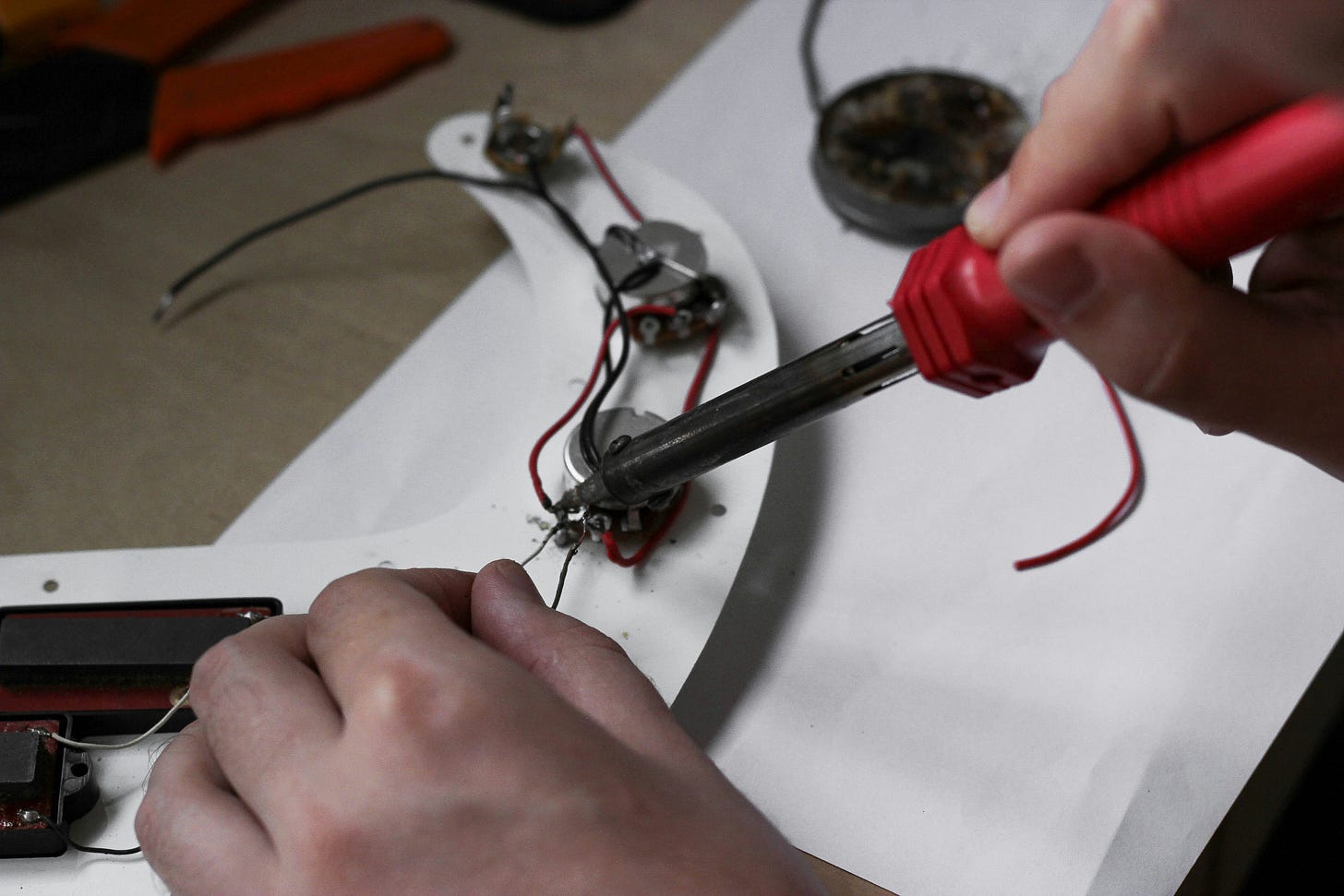 Hands using a soldering iron to repair wiring on a small device, symbolizing careful, hands-on troubleshooting and fixing.