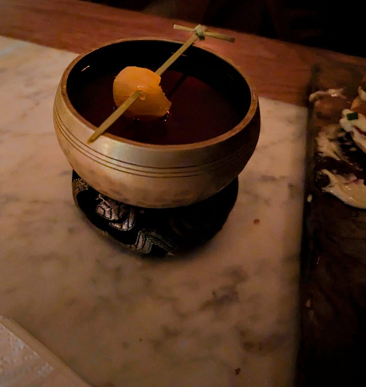 Left to right: An aloe leaf pops out of a glass in the shape of a woman's behind; A small orange peel suspended by a toothpick over a bowl
