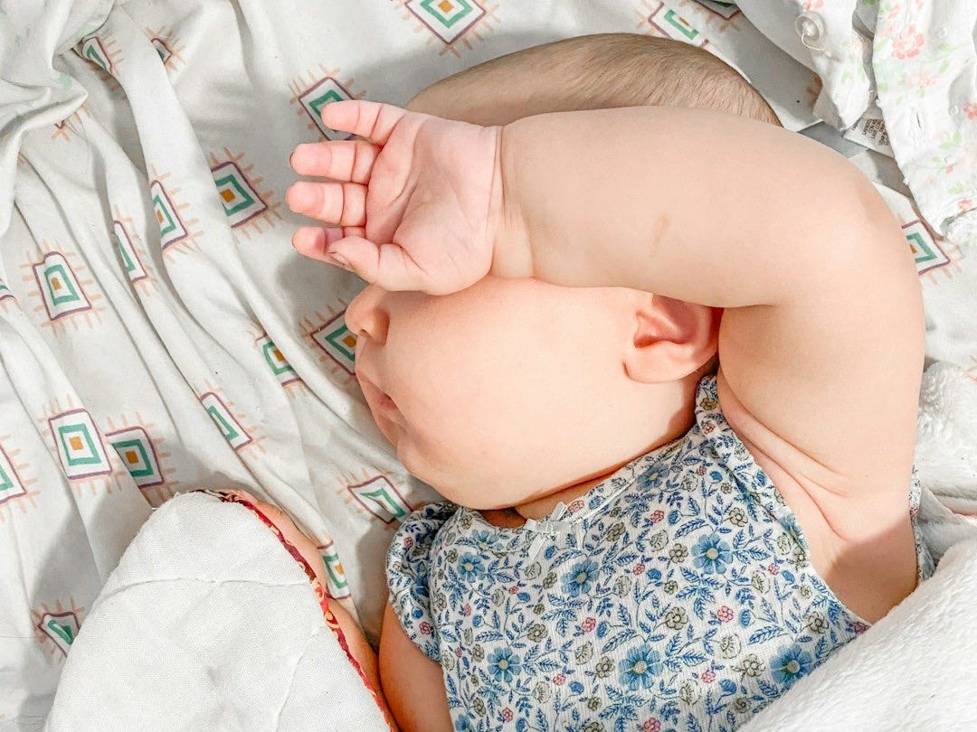 a baby laying on a bed with a white blanket