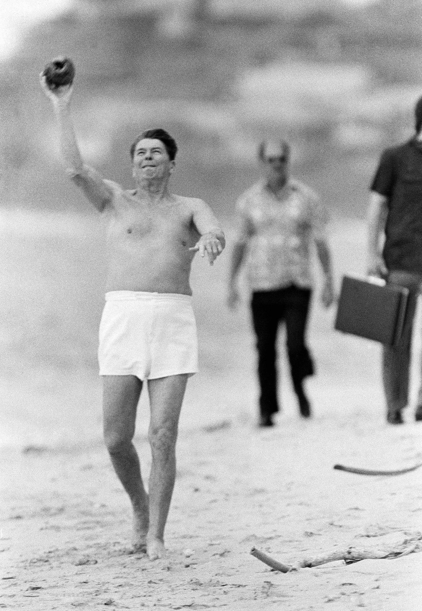 President Ronald Reagan playfully tosses a coconut during a midday break at Kahala Beach, Honolulu, Hawaii, amidst a stroll and swim, April 23, 1984. President Ronald Reagan playfully tosses a coconut during a midday break at Kahala Beach, Honolulu, Hawaii, amidst a stroll and swim, April 23, 1984.