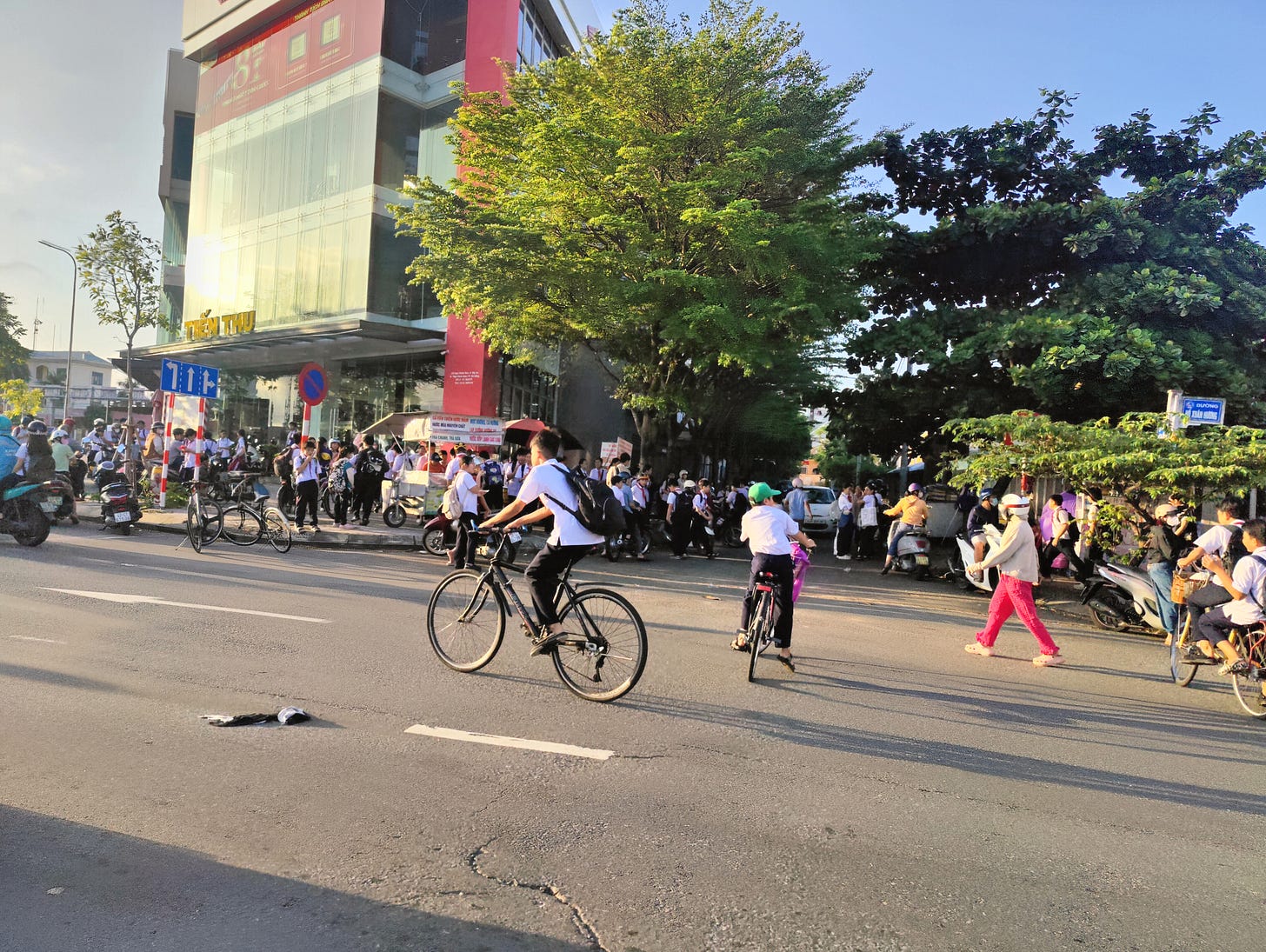 a young Vietnamese boy rides a bicycle on a sunny day in front of a busy school a young Vietnamese boy rides a bicycle on a sunny day in front of a busy school