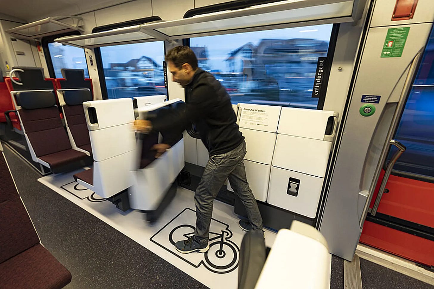 Un monsieur depliant un siege dans le train pour faire place a une place pour velo