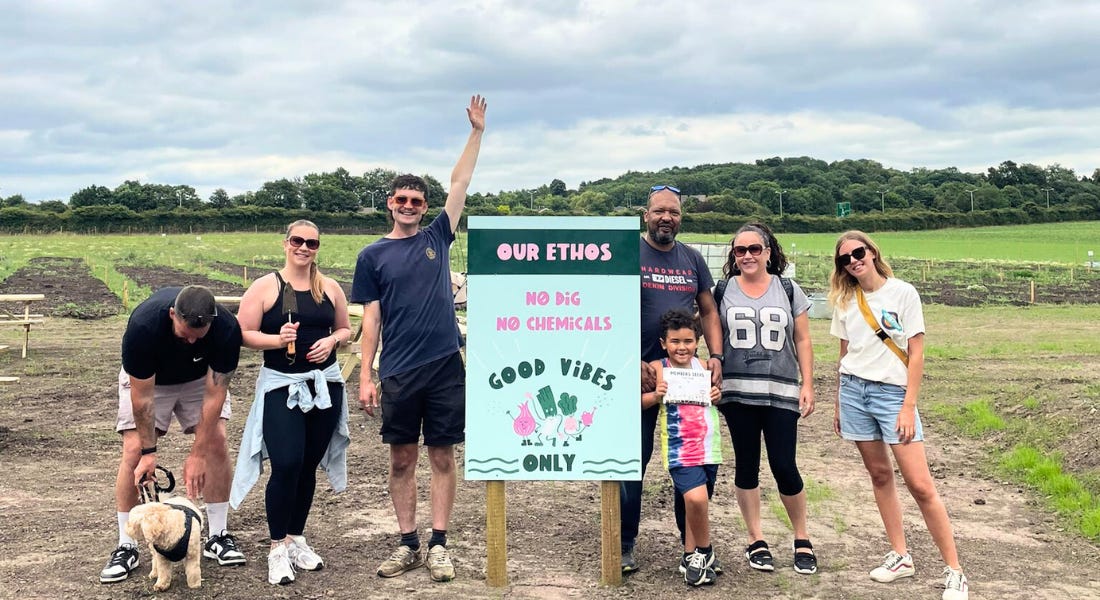 Six people standing in front of a blue board that says 'good vibes only' in a field
