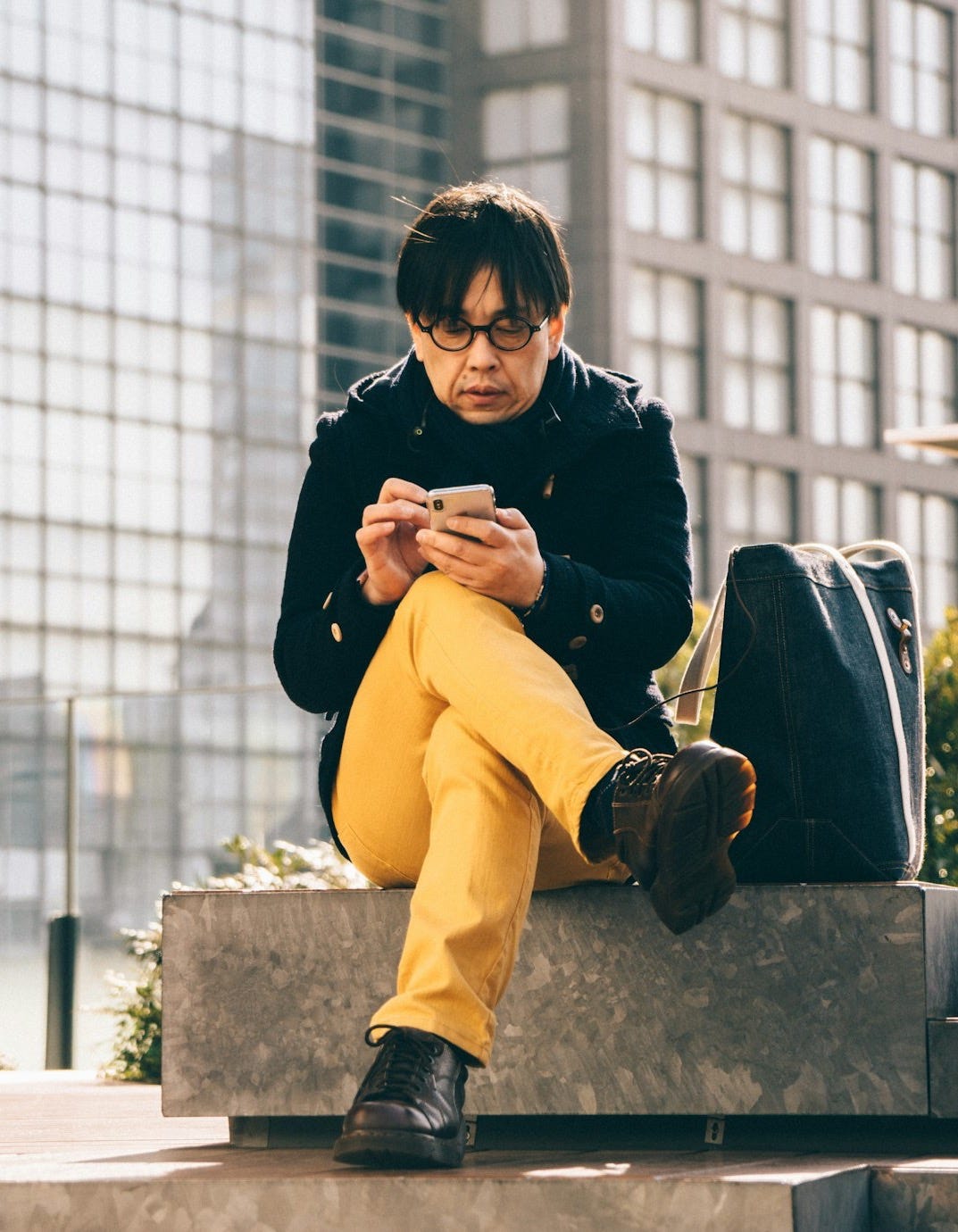 man using smartphone sitting on concrete bench