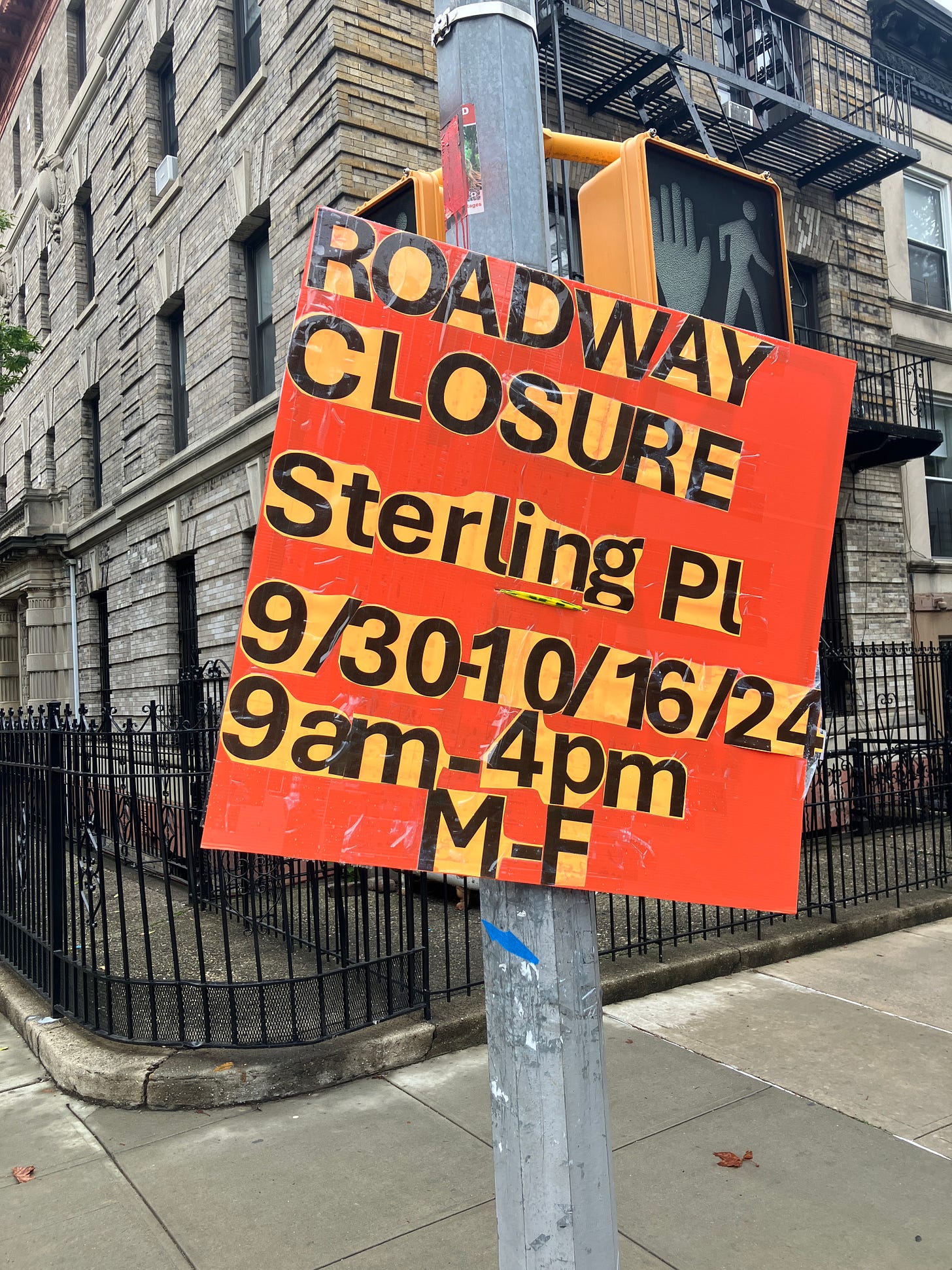 On a fluorescent orange background, black sans serif text on a lighter orange background has been cut out and stuck down reading "ROAD CLOSURE sterling pl" and giving the dates and times