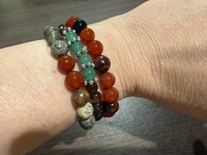 A variety of bead bracelets in various colors and pink mala beads and tiger's eye mala beads