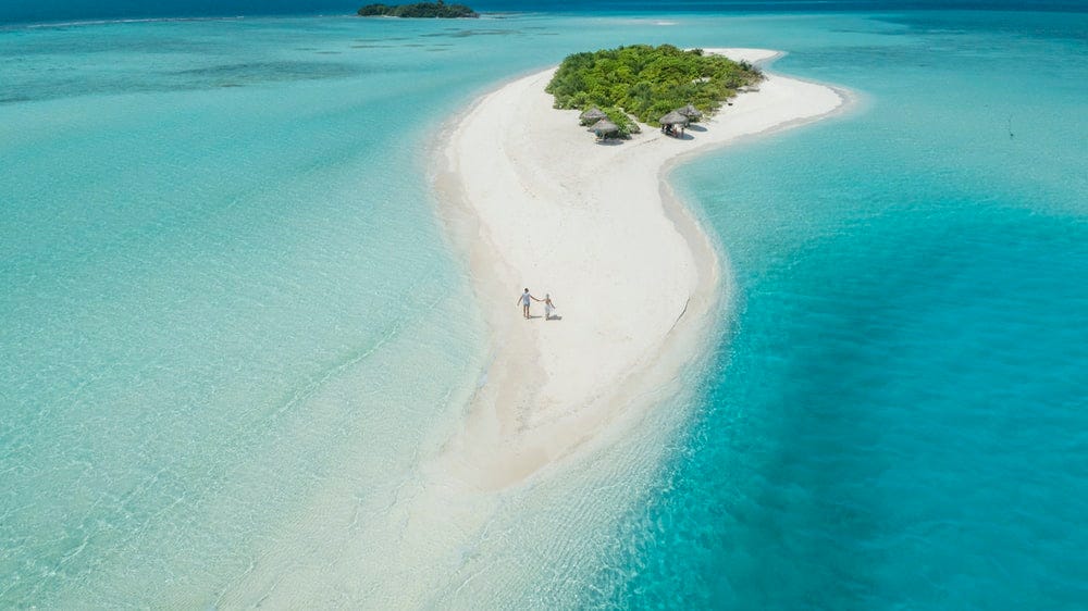 two person walking on islet during daytime two person walking on islet during daytime