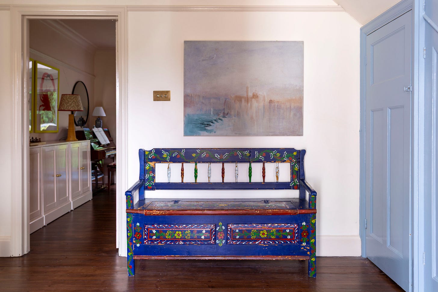 blue vintage folk bench in an entrance hallway with blue cupboards