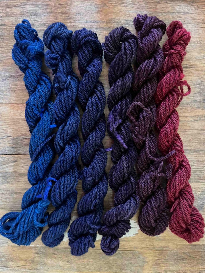 Two sets of 6 skeins of yarn, in a gradient from raspberry red to a royal blue. One set is darker.