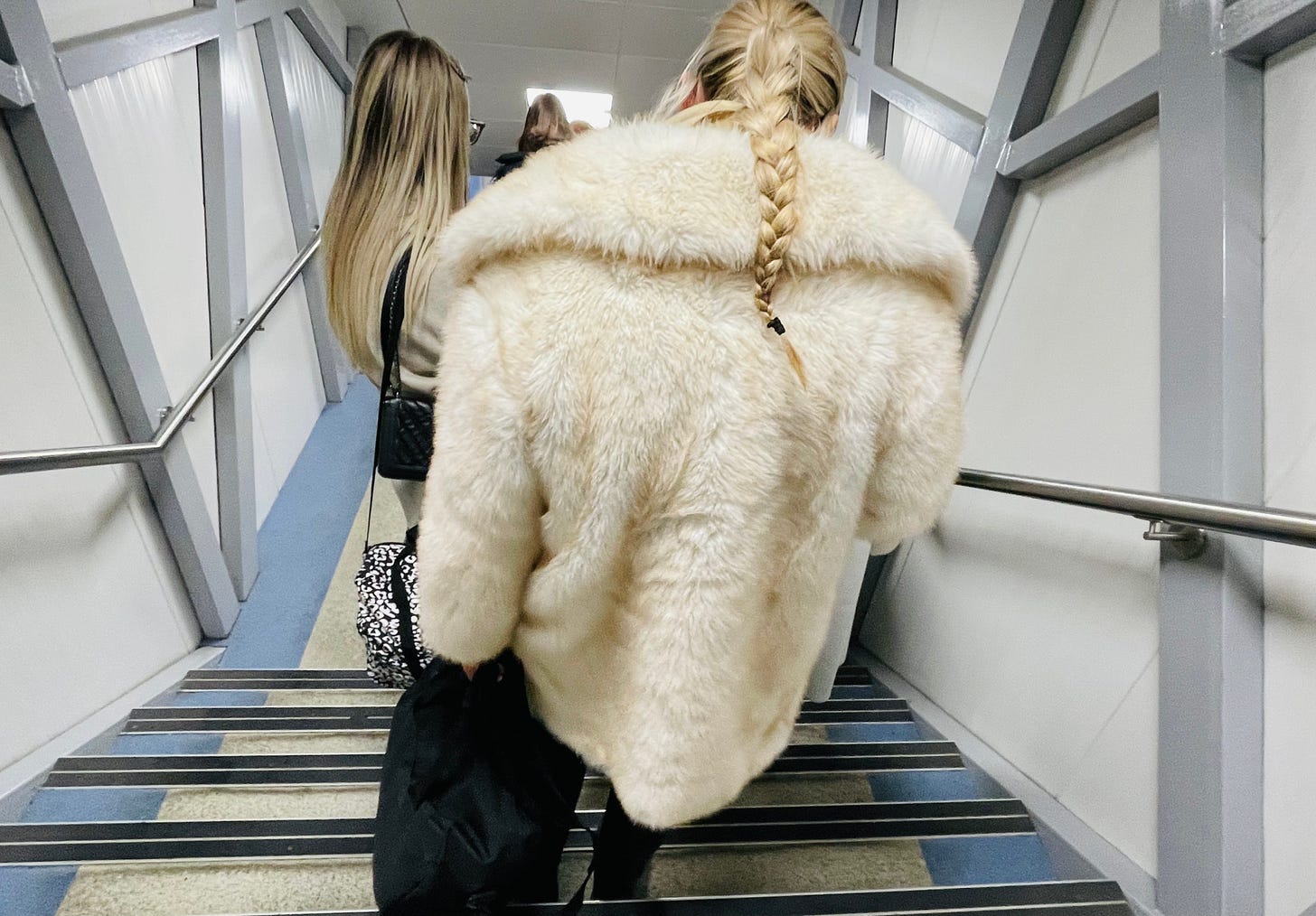 A woman in a heavy cost depends a flight of stairs