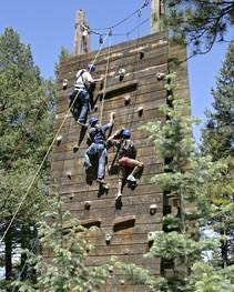Three climbers roped together on a climbing wall.