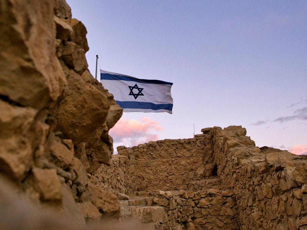 an israeli flag flying over a rocky area an israeli flag flying over a rocky area