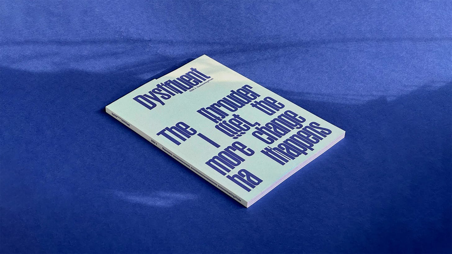 A magazine on a dark blue surface. Its front cover is light seagreen with dark blue typography. A magazine on a dark blue surface. Its front cover is light seagreen with dark blue typography.