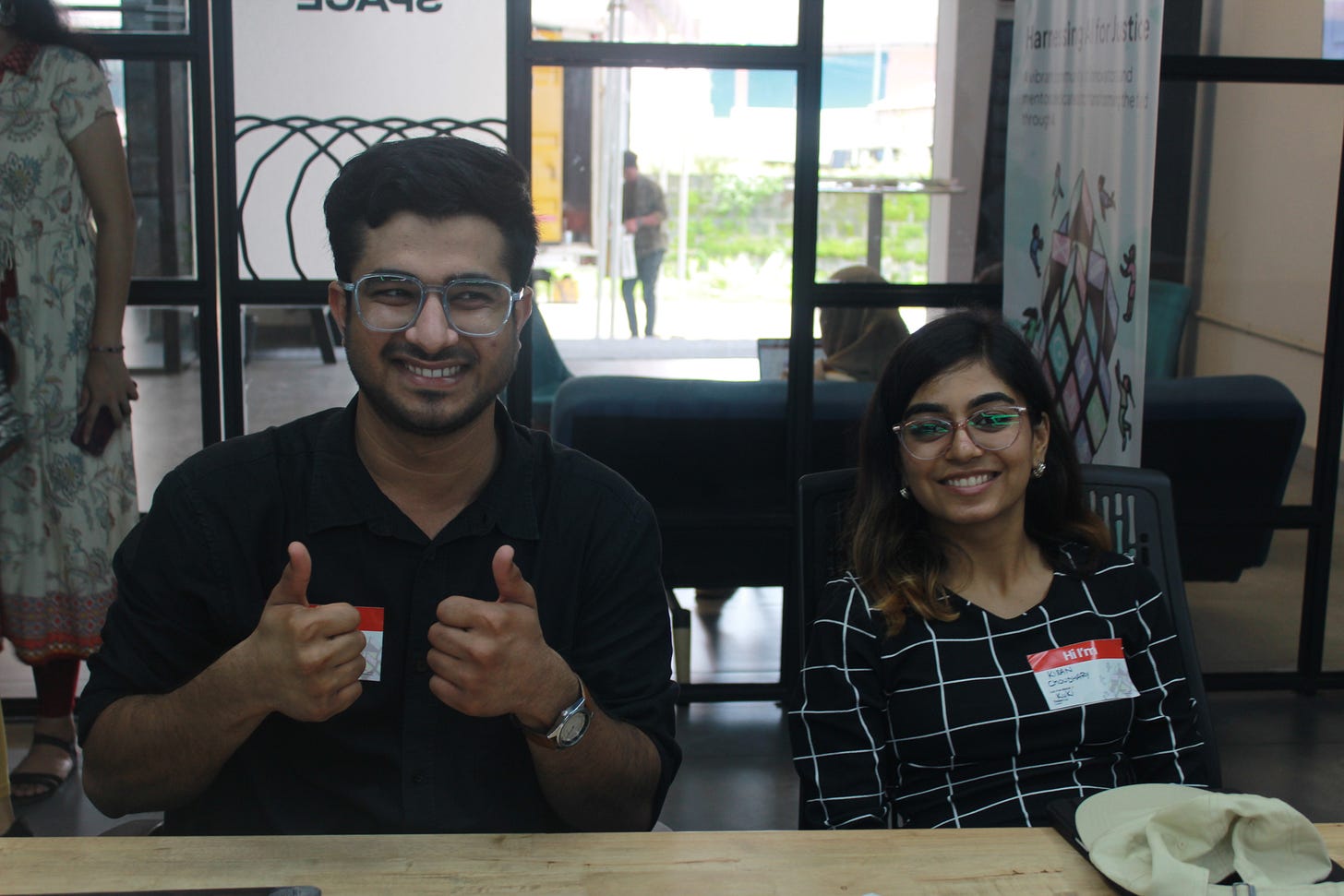 Two people sitting at a table giving thumbs up