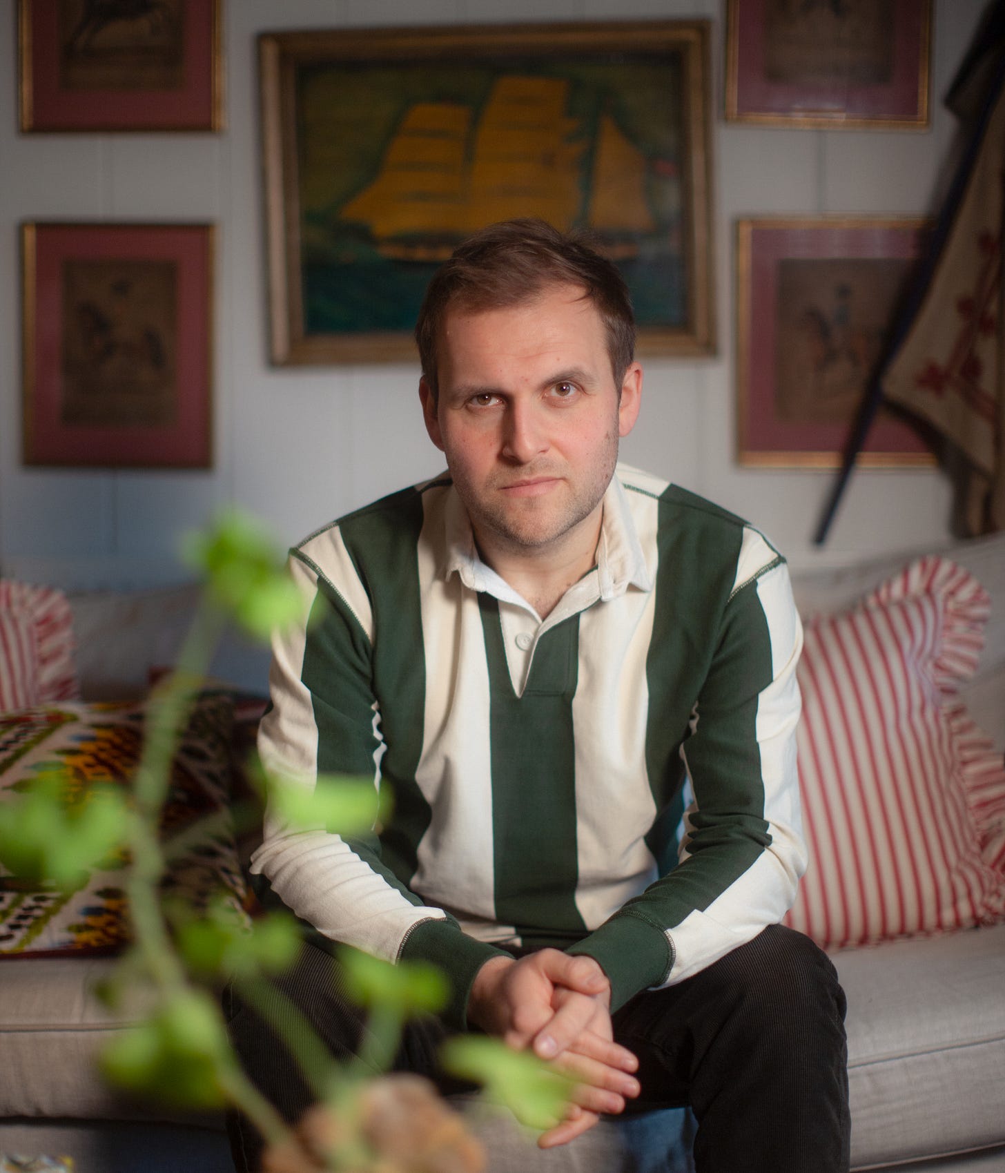 author in black and white stripes shirt sitting on a sofa 