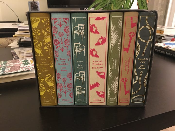 Seven multi colored clothbound books in a printed box.