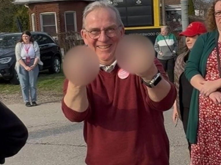 Mark Carney and Liberal supporter, believed to be Matt Janes from St. Thomas, Ont., gives two middle fingers to camera.