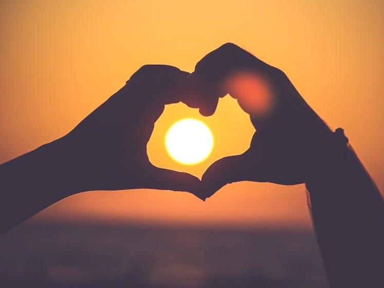 silhouette of person's hands forming heart