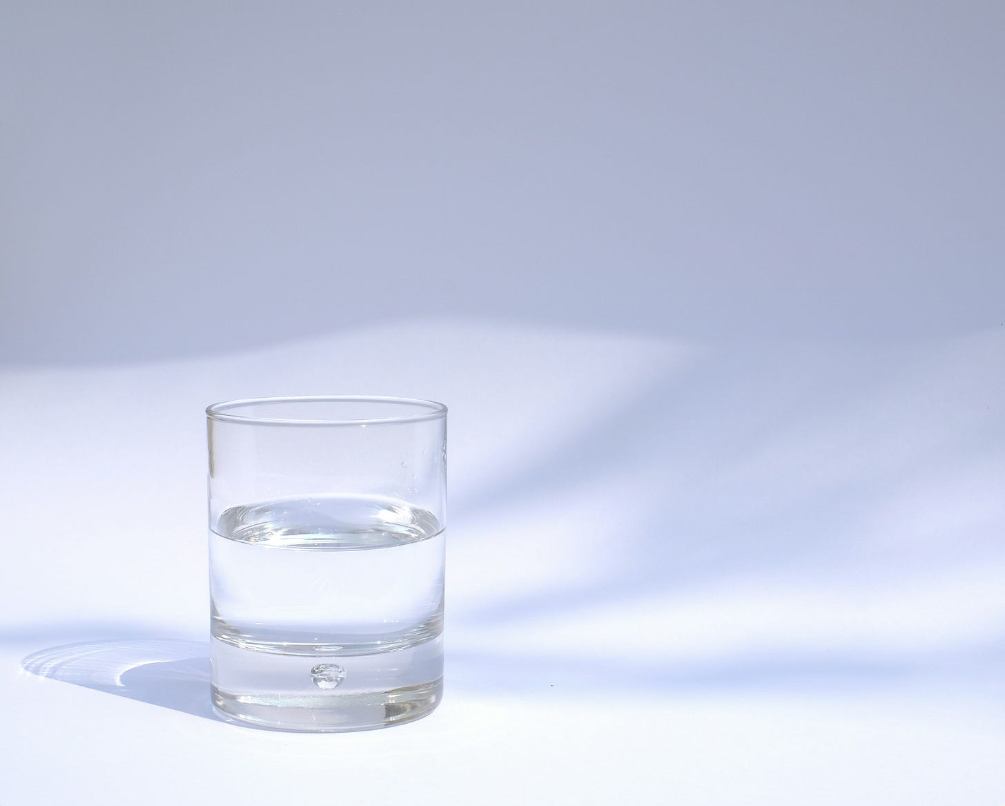 Half a glass of water set against a white backdrop.