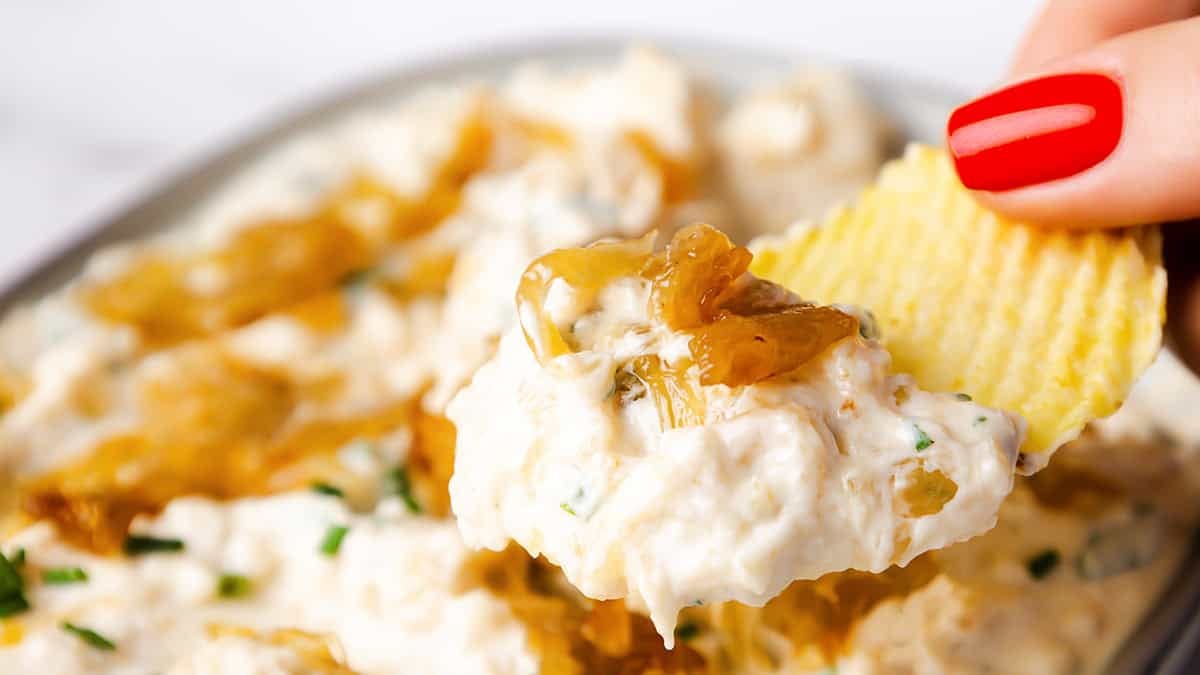 Ridged potato chip dipped into creamy caramelized onion dip topped with sweet caramelized onions and fresh chives.