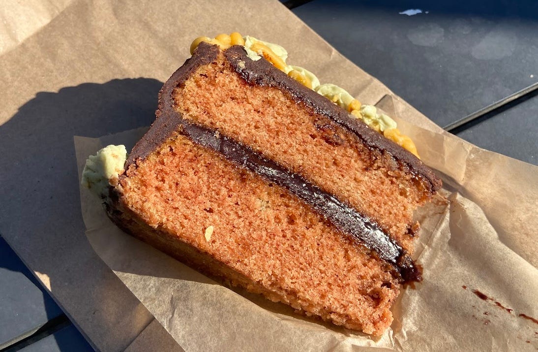 A slice of chocolate pumpkin spice cake sits atop a sheet of brown wax paper.