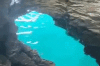 A person diving into the ocean between rocks