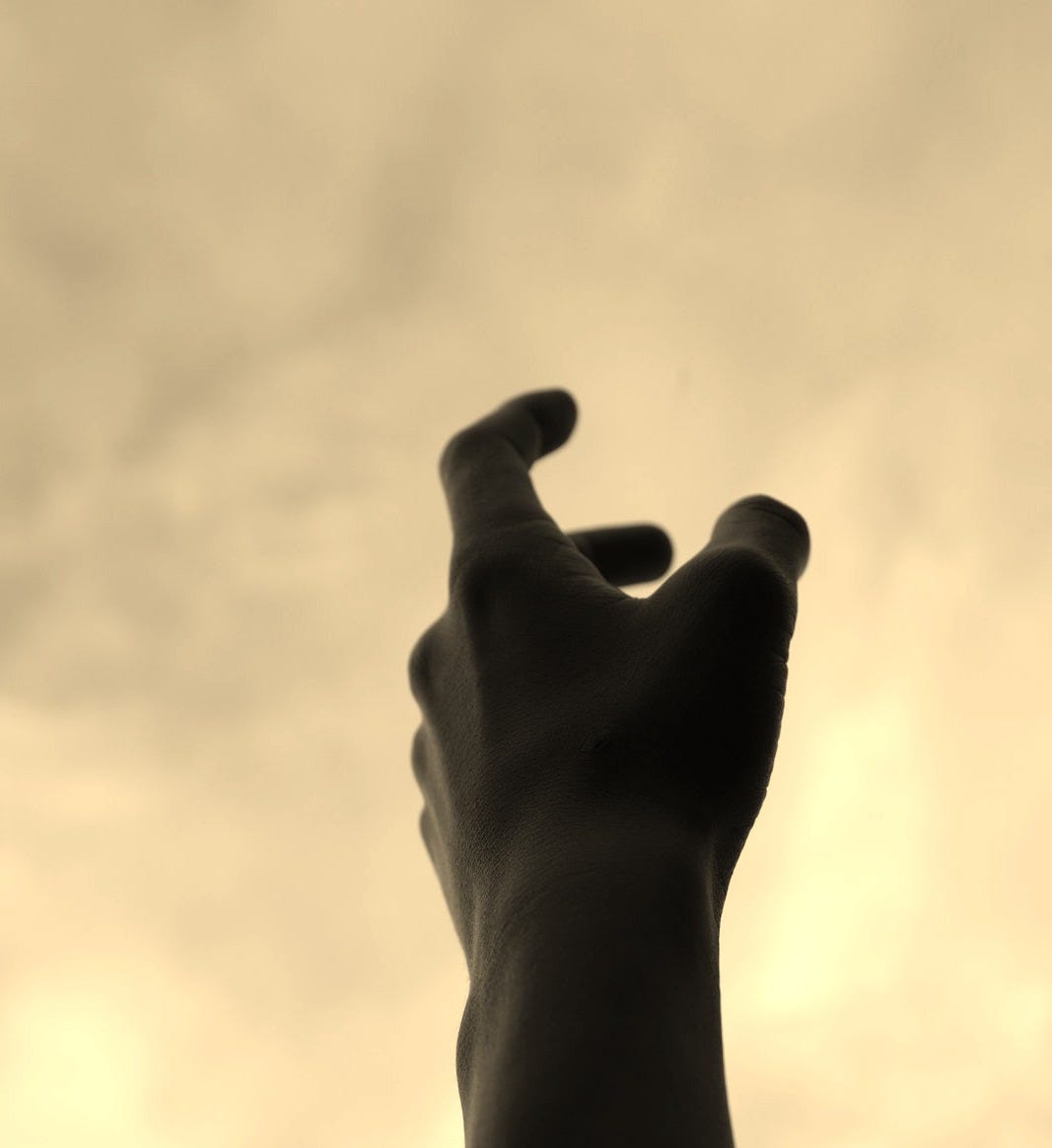 A hand reaching up towards a cloudy sky