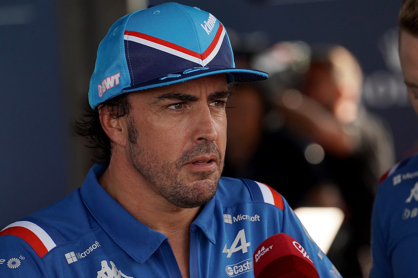 Fernando Alonso wearing Alpine-branded clothing speaks into a microphone in the F1 media pen Fernando Alonso wearing Alpine-branded clothing speaks into a microphone in the F1 media pen