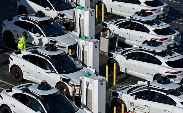 Waymo robotaxis sit parked at a Waymo facility. Waymo robotaxis sit parked at a Waymo facility.