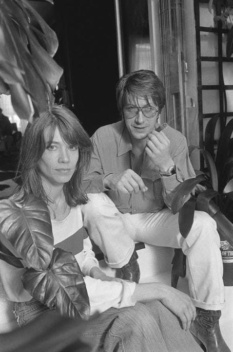 This may contain: two people sitting next to each other in front of a window with plants behind them This may contain: two people sitting next to each other in front of a window with plants behind them