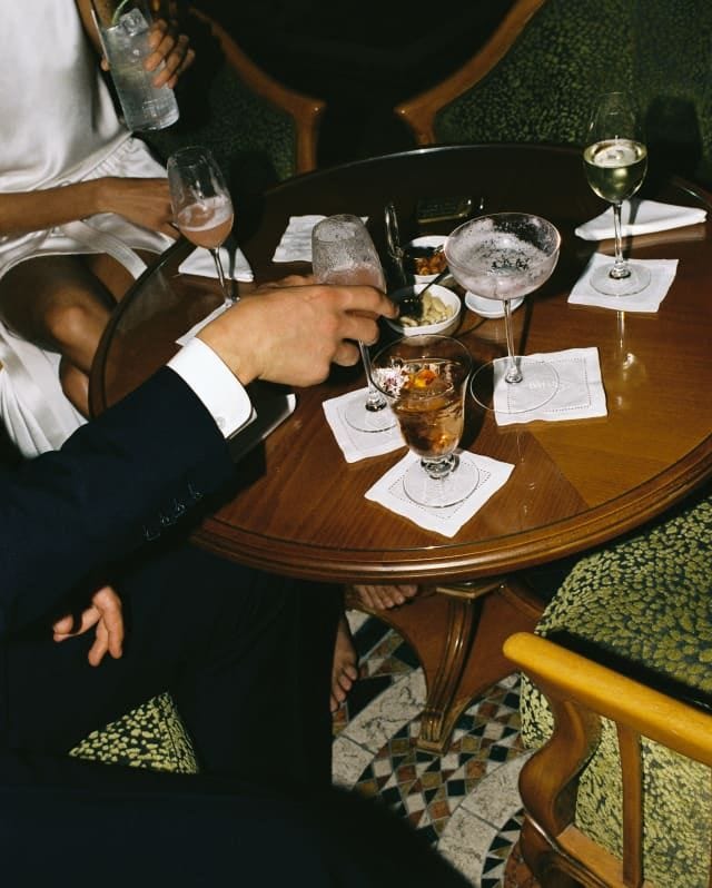 This may contain: two people sitting at a table with drinks This may contain: two people sitting at a table with drinks