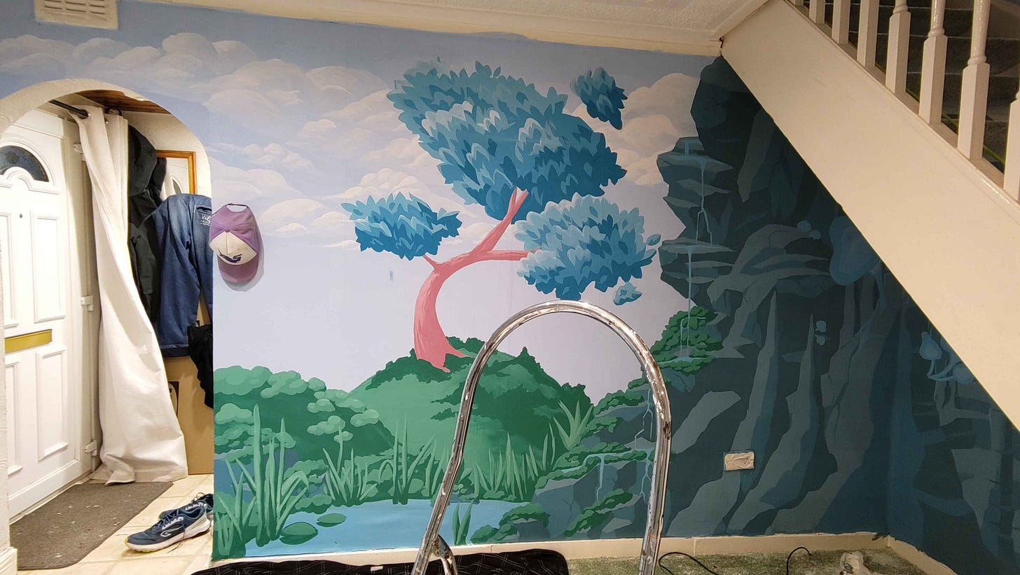 our dining room wall which has been painted to look like a painterly scene with a lone blue-leaved tree atop a grassy hill. A deep cave full of glowing mushrooms can be seen under the stairs.