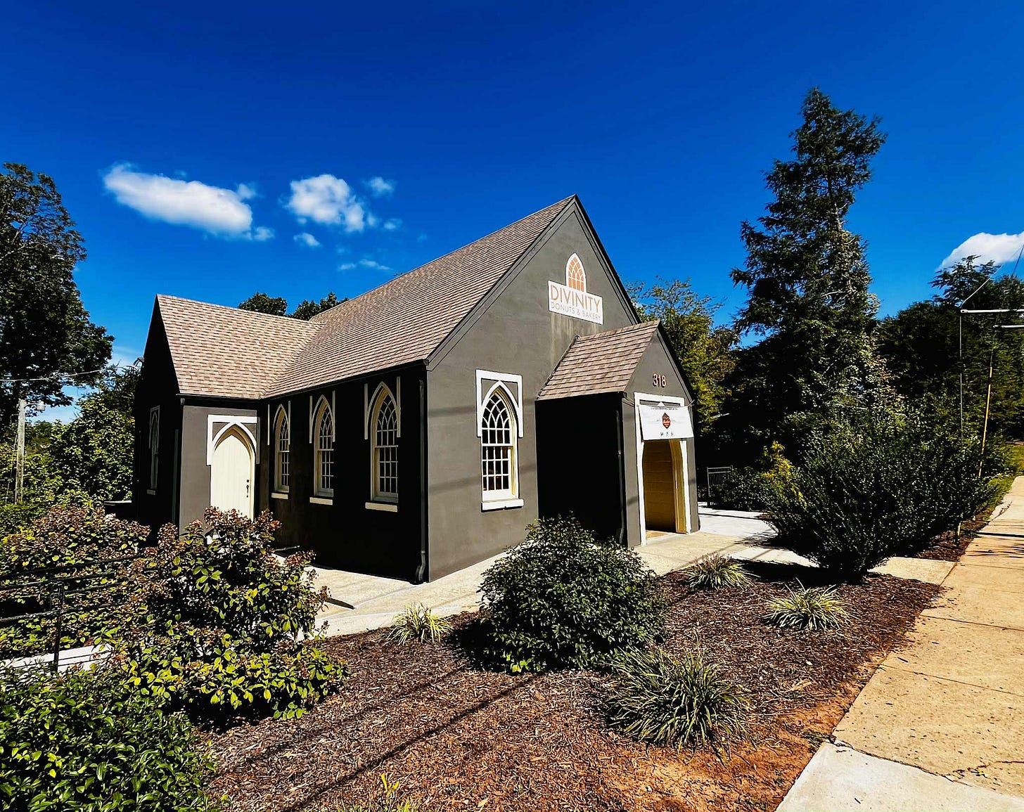 Exterior of the Titled Map, a one-story black building with Gothic-arched windows.