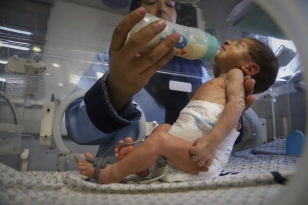 A nurse feeds a prematurely born baby lying in an incubator at the neonatal intensive care unit of Nasser Hospital in Khan Younis, southern Gaza Strip, Thursday, June 19, 2025. (AP Photo/Mariam Dagga, File)