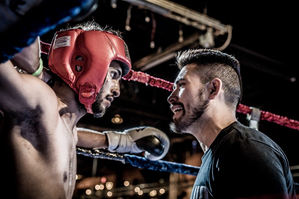 Photo of a boxer being supported by his coach during a fight