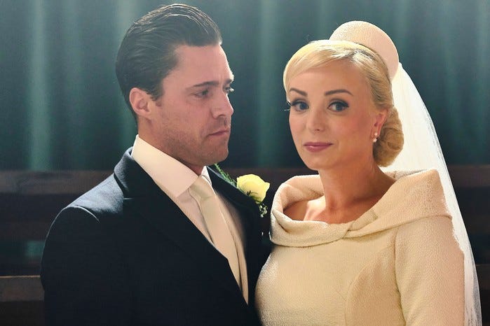 Trixie and Matthew wearing their wedding outfits and standing next to one another